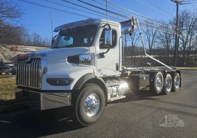 White heavy-duty hook lift truck on a road.