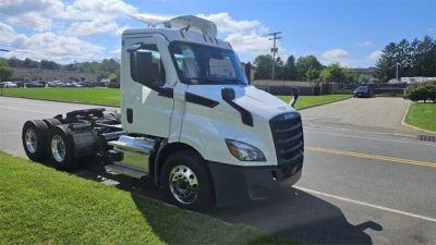 White semi-truck parked on grass beside road.