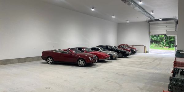 Five cars parked inside a spacious, brand new storage facility.