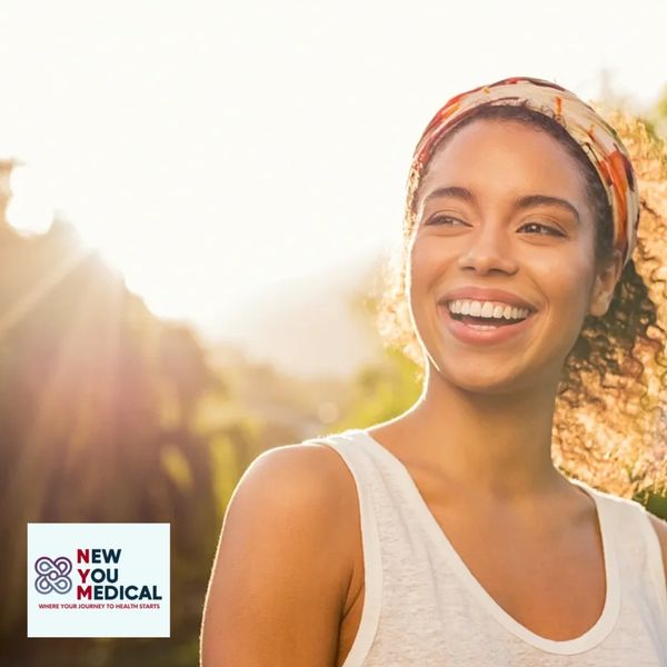 Smiling woman outdoors with sunlight and New You Medical logo.