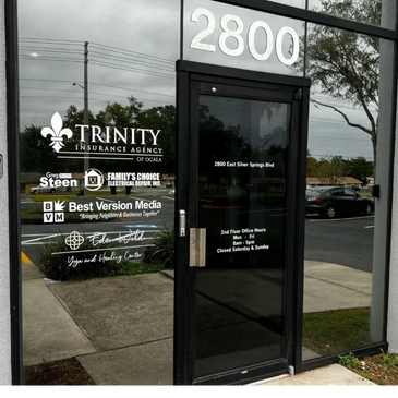 Office building entrance with business names and hours on glass door.