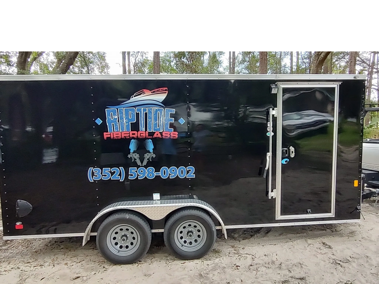 Black trailer with Riptide Fiberglass logo and phone number on the side.