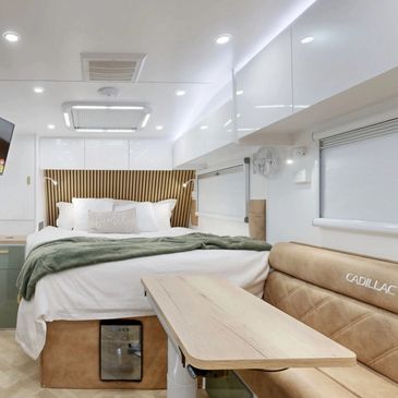 Modern Cadillac RV interior with cozy bed and classy  coastal dining area.