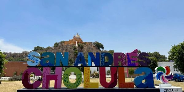 Letras coloridas de San Andrés Cholula frente a un cerro con edificio.