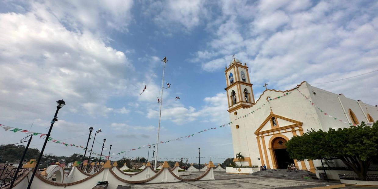 Voladores de Papantla realizando su ritual frente a una iglesia.