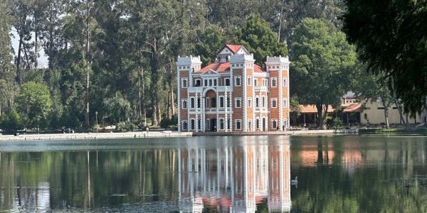 Castillo reflejado en un lago rodeado de árboles.
