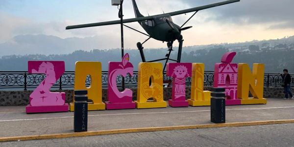 Letras grandes que forman "ZACATLAN" con un helicóptero arriba.