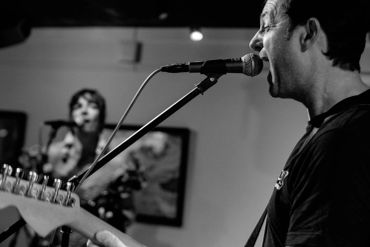 Man passionately singing into a microphone while playing guitar.