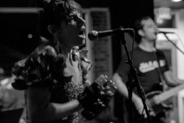 Black and white photo of a woman singing into a microphone.