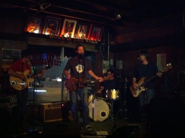 Band performing live on a dimly lit stage.