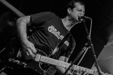 Man passionately singing and playing electric guitar.