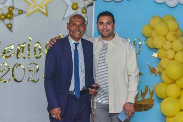 Two men smiling at a senior event with balloons.