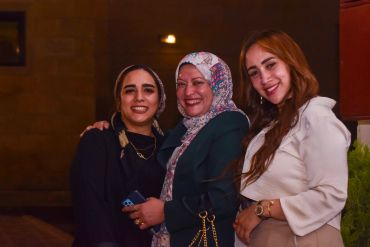 Three women smiling and posing together.