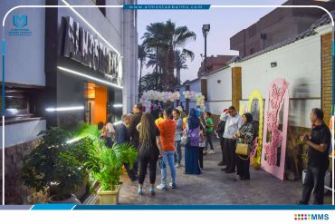 People gathering outside a venue decorated with balloons and art.