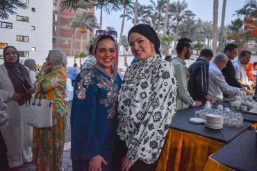 Two women smiling at an outdoor gathering.