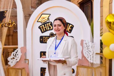 Smiling woman in beige outfit holding a document.