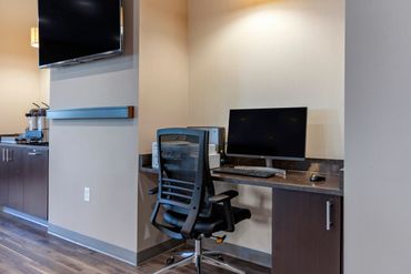 Modern workspace with computer, office chair, and coffee station in a corner.