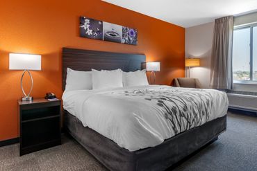 Modern hotel room with an orange accent wall and king-sized bed.