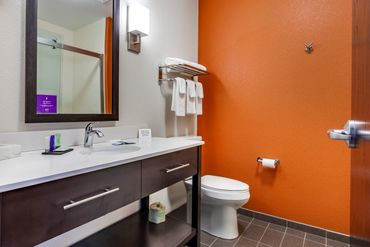 Modern bathroom with orange accent wall and white fixtures.