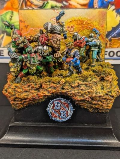Detailed fantasy miniatures battle scene on textured base.