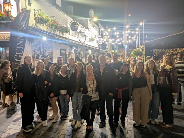 Group of friends posing outside a pub at night.
