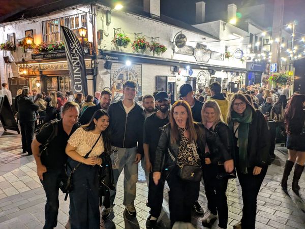 Group of friends posing happily outside a pub at night.