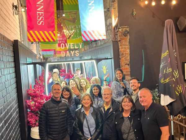 Group of people posing happily indoors with colorful banners overhead.