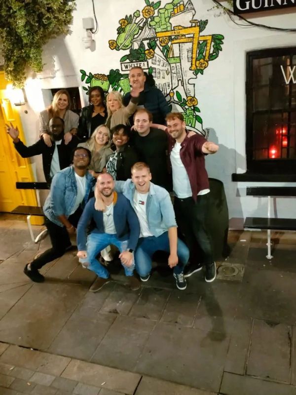 Group of friends posing outside a pub at night.