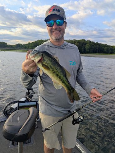 Man holding a largemouth bass on a boat.