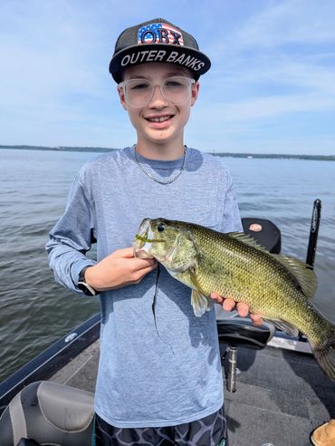 Boy holding a large fish on a boat.
