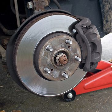 Close-up of a car brake disc and caliper during maintenance.