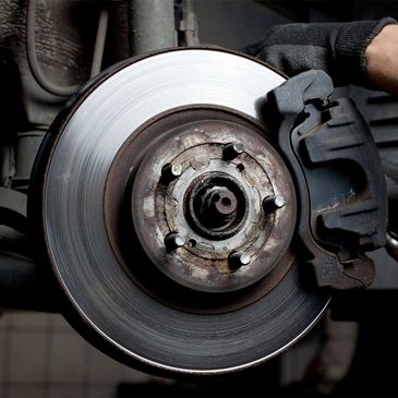 Close-up of a car brake disc and caliper during maintenance.