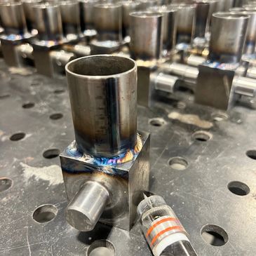 Close-up of welded metal components on a perforated workbench.