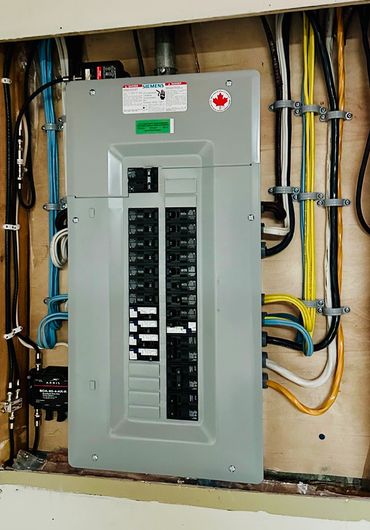 Electrical panel with circuit breakers and organized wiring.
