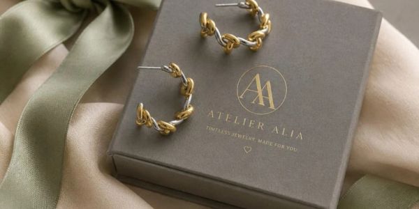 Gold twisted hoop earrings on a branded box.