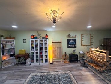 Cozy craft room with shelves, weaving loom, and eclectic decorations.