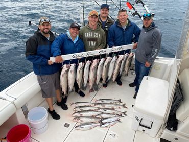 Guys holding a full rack of fish with more on the deck after Lake Michigan Charter Fishing trip