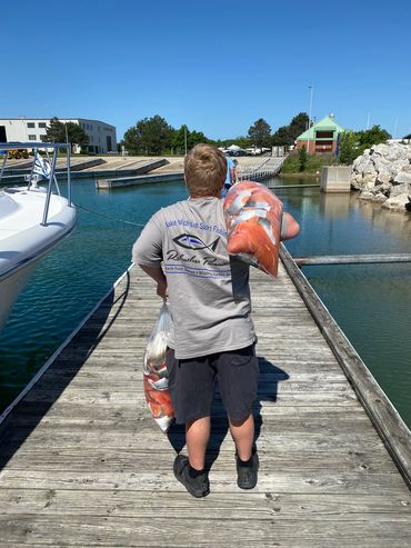 Young boy carrying fish down the dock after Lake Michigan charter fishing trip