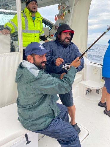 Two guys holding the rod during Lake Michigan Charter Fishing trip