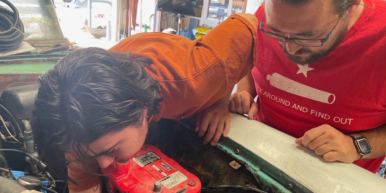  A mentor helping a younger man repair a 1955 Pontiac Chieftain