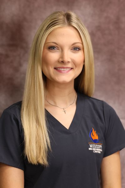 Young woman in a Mississippi College nursing scrub top smiling.