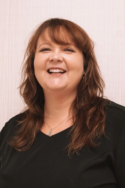 Smiling woman with medium-length brown hair wearing a black top.