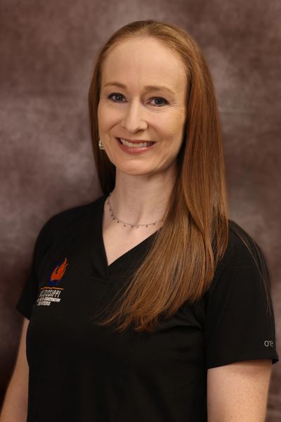 Smiling woman with long red hair wearing a black Mississippi State shirt.