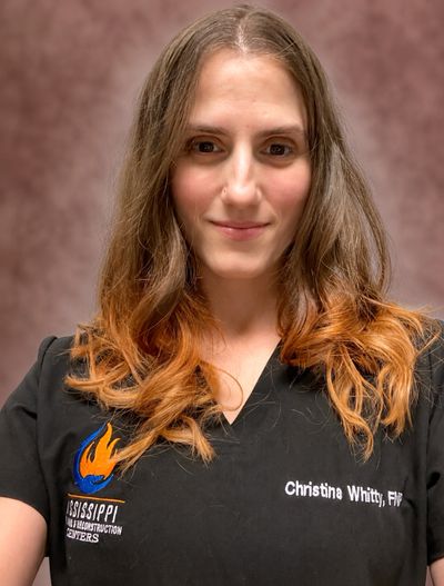 A woman with ombre hair wearing a black medical uniform with a name tag.
