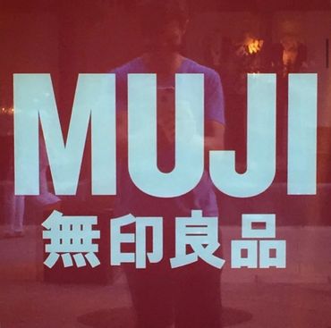 MUJI store sign with Japanese characters on a reflective surface.