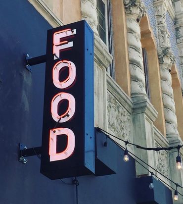 Neon sign reading 'FOOD' on an ornate building facade.
