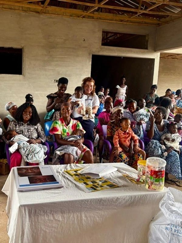 Community gathering with mothers and children in a hall.