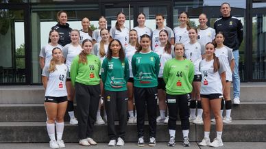 A women's handball team posing together for a group photo outdoors.