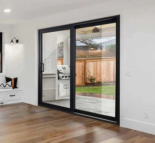 Modern interior with wooden floor and large glass sliding door to backyard.