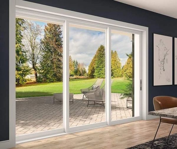 Modern living room with large sliding glass door opening to a patio and green backyard.
